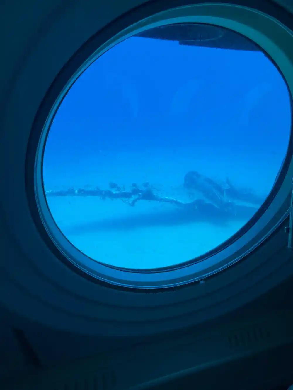 A wreck seen through the round viewport at depth